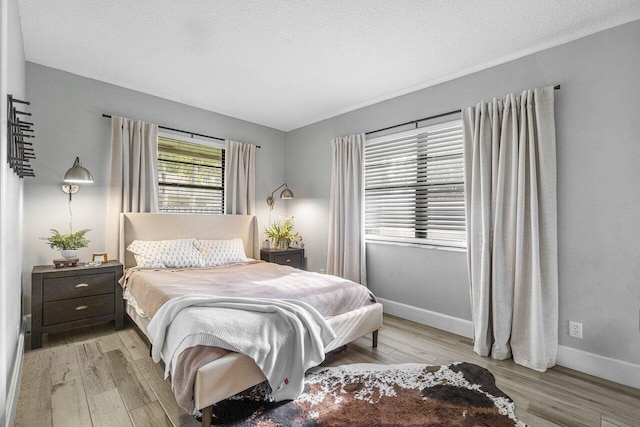 bedroom with a textured ceiling and light hardwood / wood-style flooring