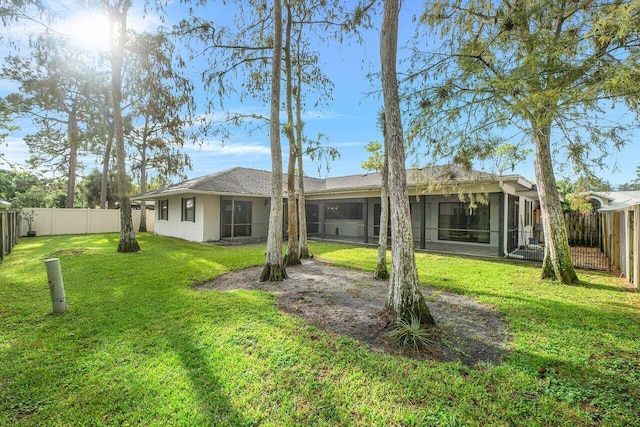 rear view of house with a sunroom and a lawn