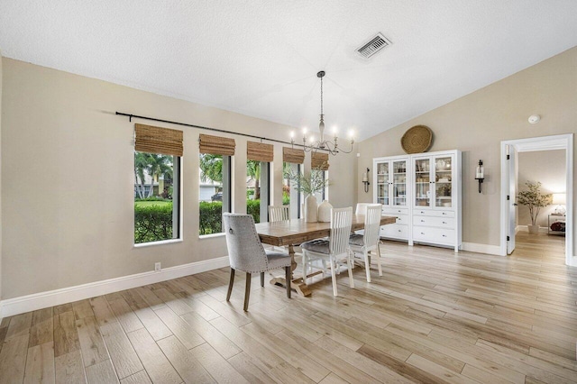 dining area with a textured ceiling, high vaulted ceiling, an inviting chandelier, and light hardwood / wood-style flooring