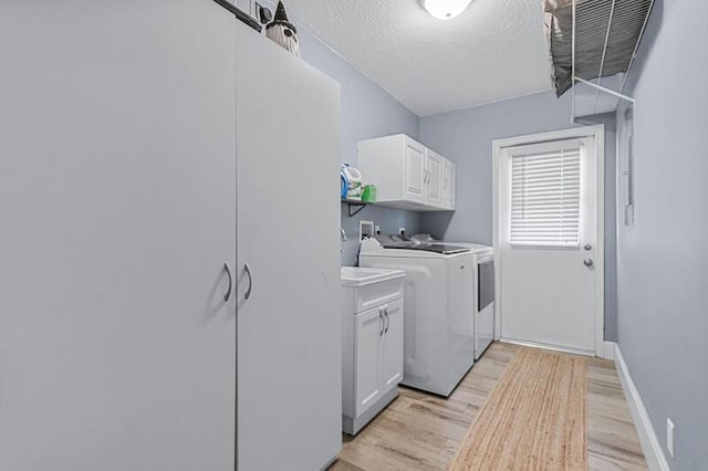 laundry area featuring cabinets, light hardwood / wood-style floors, a textured ceiling, and independent washer and dryer