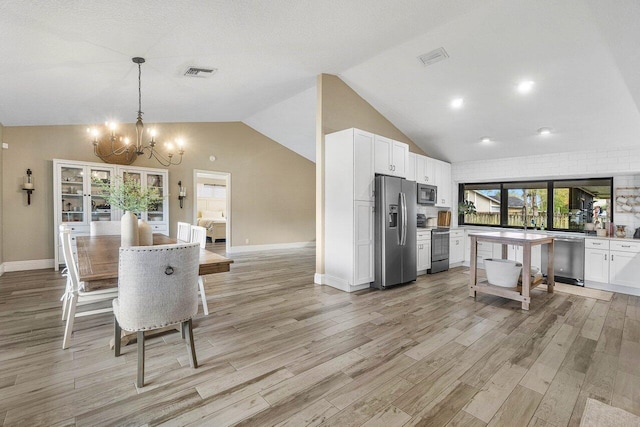 dining area featuring light hardwood / wood-style flooring, high vaulted ceiling, and an inviting chandelier