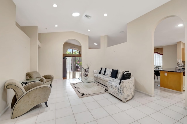 tiled living room featuring sink and vaulted ceiling