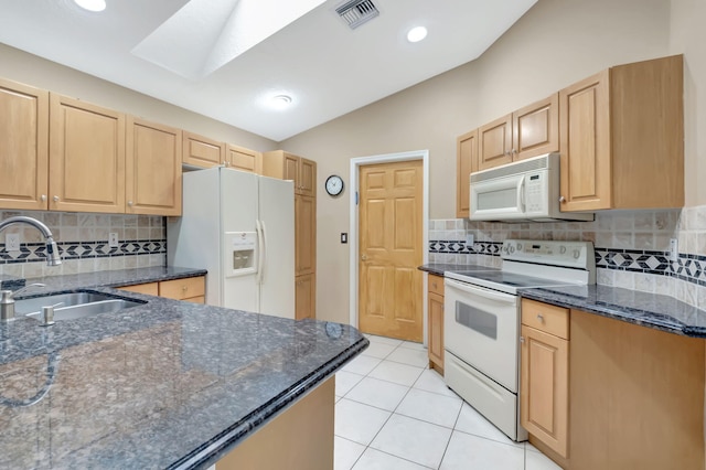 kitchen with vaulted ceiling with skylight, white appliances, sink, and tasteful backsplash