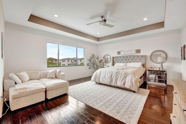 bedroom featuring ceiling fan, dark hardwood / wood-style flooring, and a tray ceiling