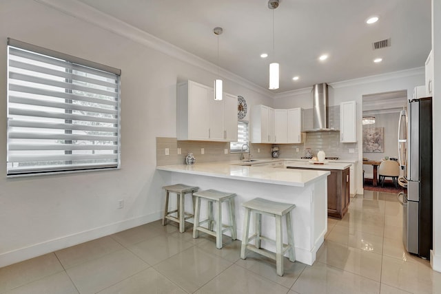 kitchen with tasteful backsplash, wall chimney exhaust hood, and white cabinets