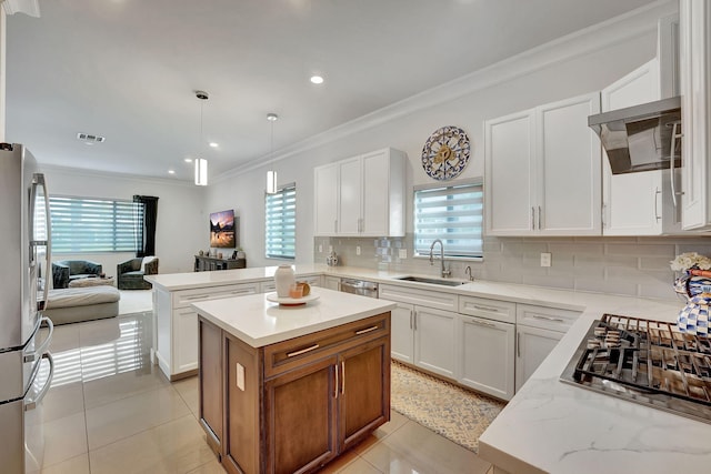 kitchen featuring stainless steel appliances, a center island, sink, backsplash, and white cabinetry