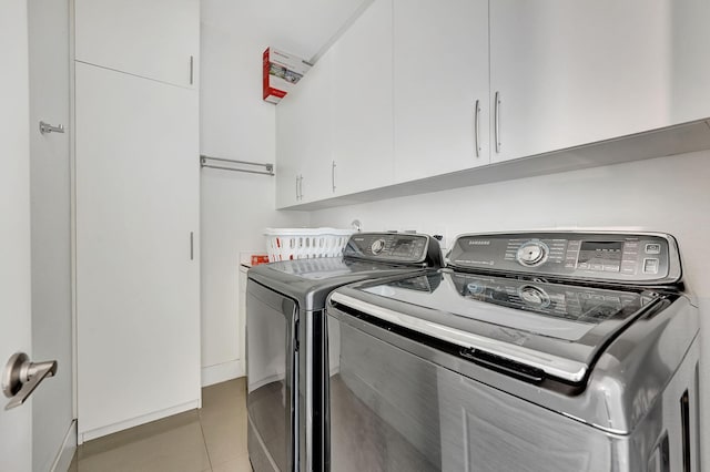 washroom with washing machine and dryer, cabinets, and tile patterned flooring