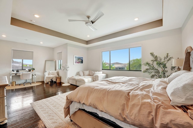 bedroom with a tray ceiling, multiple windows, ceiling fan, and dark hardwood / wood-style floors