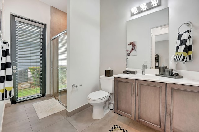 bathroom featuring vanity, a shower with shower door, tile patterned floors, and toilet