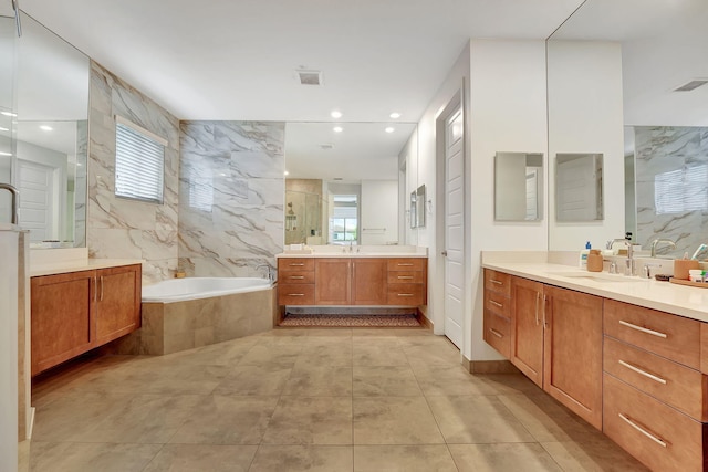 bathroom with tile walls, shower with separate bathtub, and vanity