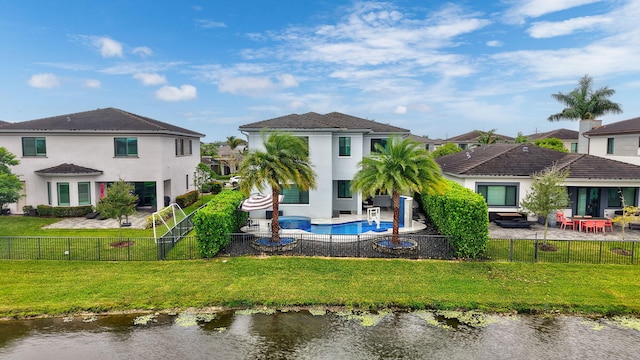 back of property featuring a lawn, a patio, and a water view