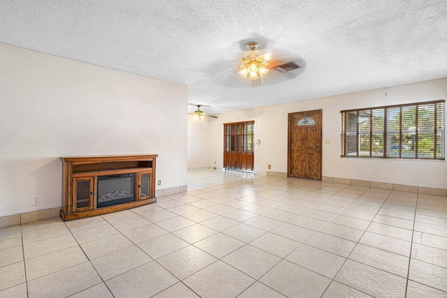 unfurnished living room featuring ceiling fan, light tile patterned floors, and a textured ceiling