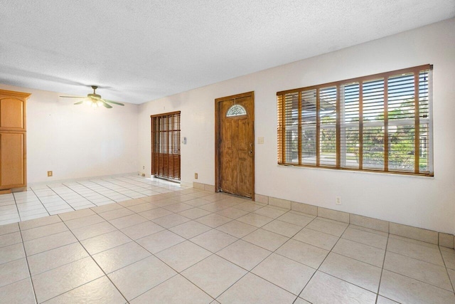 empty room featuring light tile patterned floors, a textured ceiling, and ceiling fan