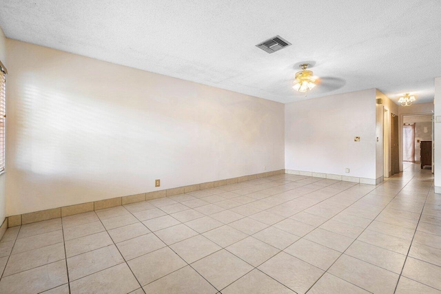 tiled empty room with a textured ceiling and ceiling fan