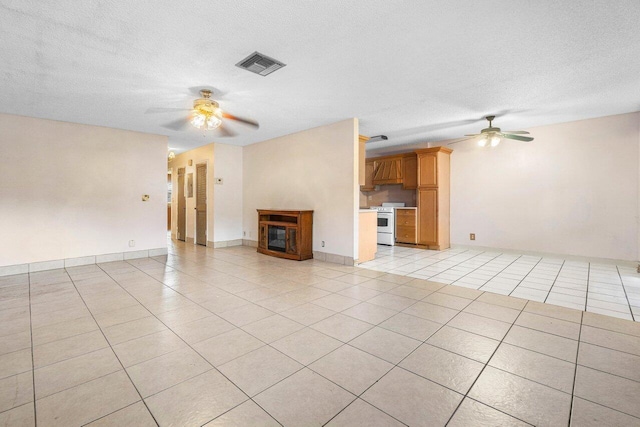 unfurnished living room with ceiling fan, light tile patterned floors, and a textured ceiling