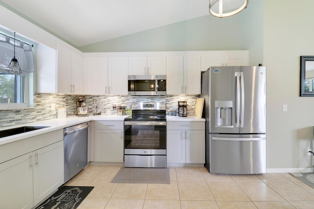 kitchen with white cabinets, vaulted ceiling, light tile patterned floors, and stainless steel appliances