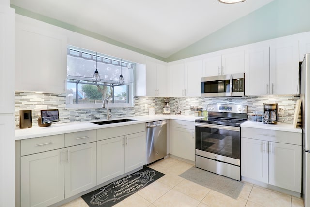 kitchen featuring appliances with stainless steel finishes, sink, vaulted ceiling, and light tile patterned floors