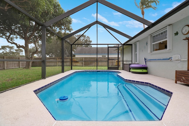 view of swimming pool with a patio, a lawn, and a lanai