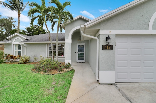 view of exterior entry featuring a garage and a lawn