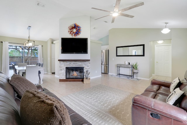 living room with ceiling fan, a stone fireplace, light tile patterned floors, and vaulted ceiling