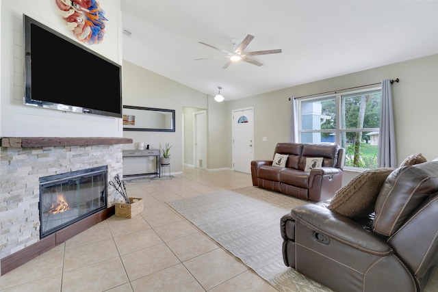 tiled living room with vaulted ceiling, ceiling fan, and a fireplace