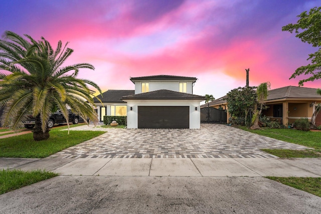 view of front of home with an attached garage, fence, decorative driveway, a lawn, and stucco siding