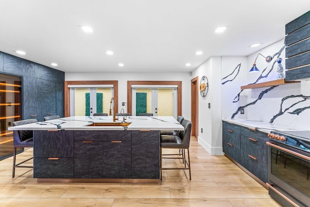 kitchen featuring stainless steel range with electric stovetop, a breakfast bar, a sink, and french doors