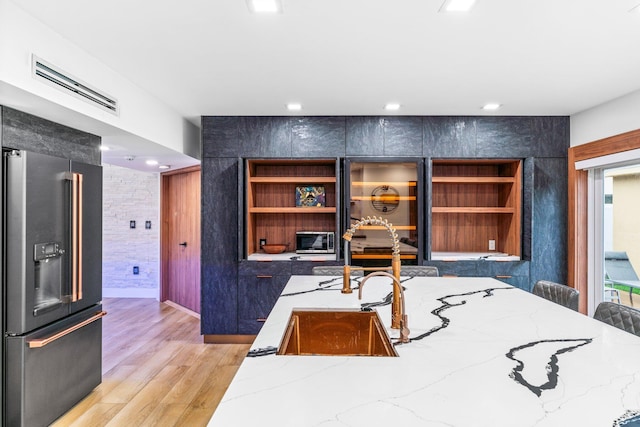 interior space featuring light wood-type flooring, high end refrigerator, visible vents, and stainless steel microwave