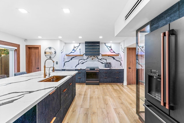 kitchen with recessed lighting, dark cabinets, light wood-style floors, black refrigerator with ice dispenser, and stainless steel range