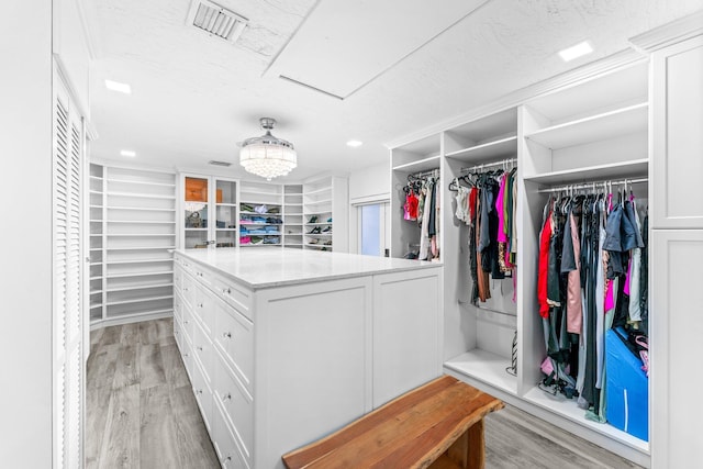 spacious closet featuring an inviting chandelier, visible vents, and light wood-style floors