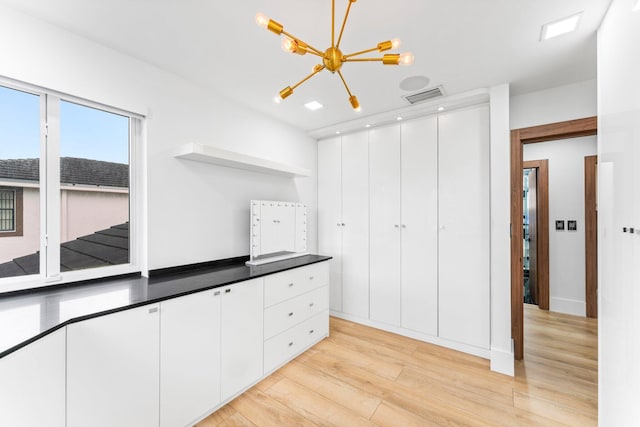 kitchen featuring light wood finished floors, open shelves, dark countertops, visible vents, and white cabinets