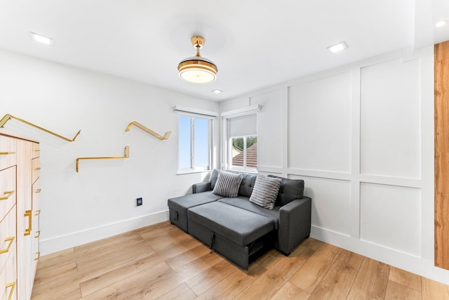 living area featuring baseboards, light wood-style flooring, and a decorative wall