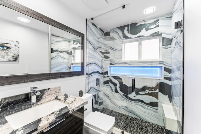 full bathroom featuring toilet, a marble finish shower, and vanity