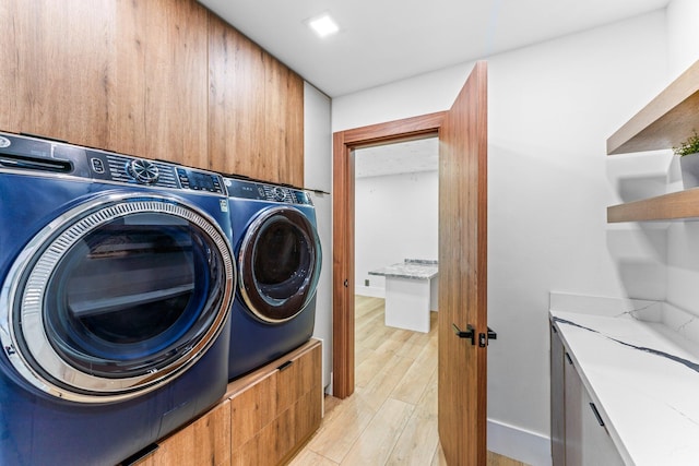 laundry room with baseboards, light wood-type flooring, cabinet space, and washer and dryer