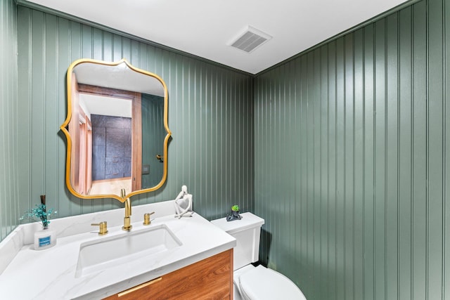 half bathroom featuring toilet, vanity, and visible vents