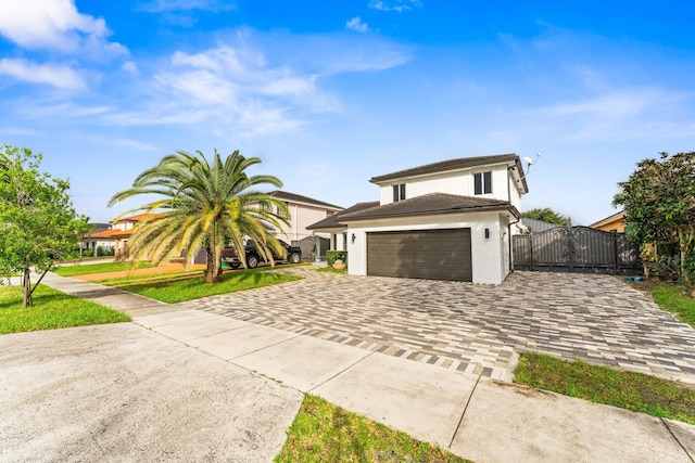 view of front of home featuring decorative driveway, stucco siding, a gate, a garage, and a front lawn