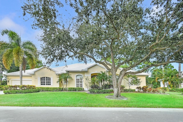 ranch-style home with a garage, stucco siding, a tiled roof, and a front yard