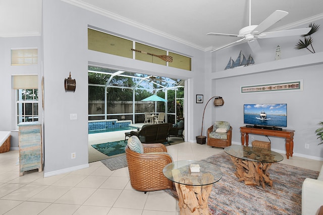 living room with crown molding, ceiling fan, light tile patterned floors, a high ceiling, and a sunroom