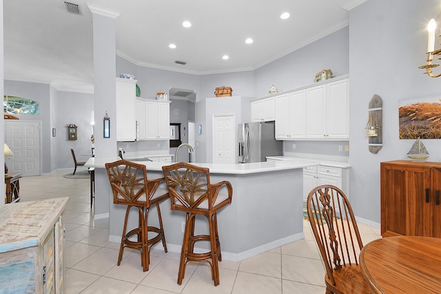 kitchen with visible vents, stainless steel fridge with ice dispenser, light tile patterned floors, a peninsula, and white cabinets