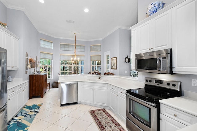 kitchen with a sink, a peninsula, ornamental molding, and stainless steel appliances