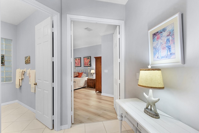 corridor with light tile patterned floors, visible vents, and baseboards