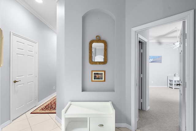 hall featuring light tile patterned flooring, light carpet, baseboards, and ornamental molding