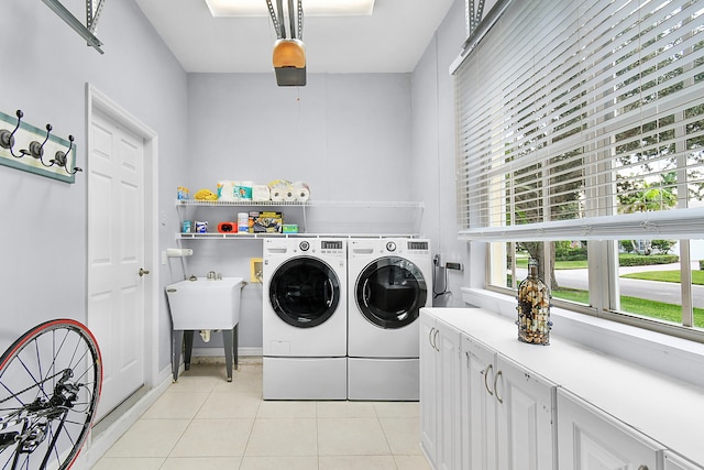 clothes washing area with cabinet space, light tile patterned floors, and separate washer and dryer