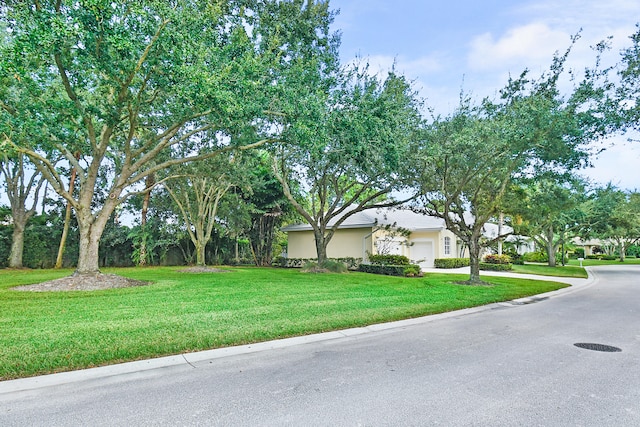 exterior space featuring a yard, a garage, driveway, and stucco siding