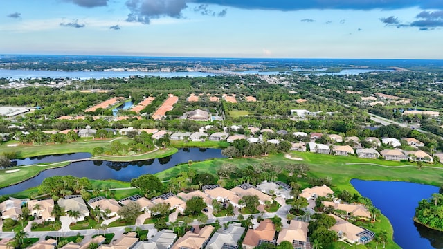 drone / aerial view with golf course view, a residential view, and a water view