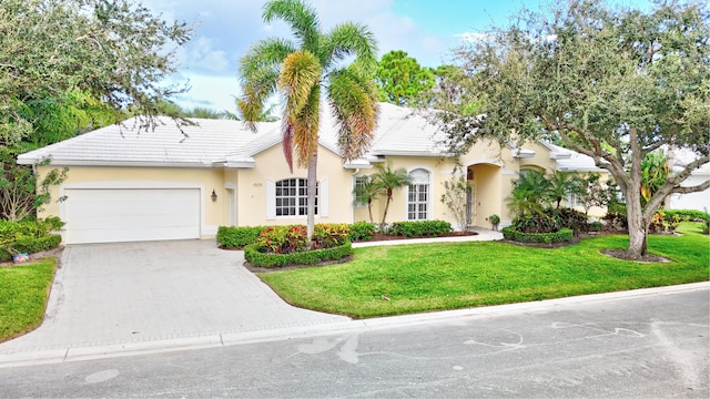 view of front of house featuring stucco siding, a front lawn, a tile roof, concrete driveway, and an attached garage