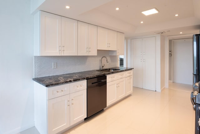 kitchen featuring dark stone counters, dishwasher, white cabinets, sink, and tasteful backsplash