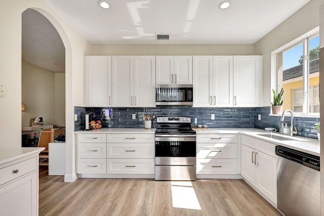 kitchen with white cabinets, light hardwood / wood-style floors, sink, and stainless steel appliances