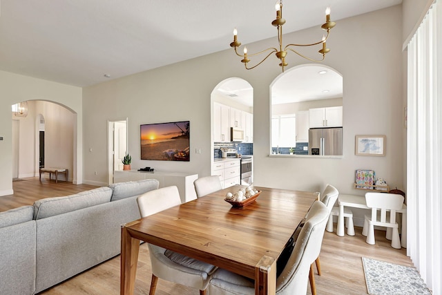 dining area featuring light wood-type flooring and a notable chandelier