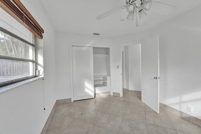 unfurnished bedroom featuring light tile patterned floors, ceiling fan, and a closet